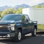 A black 2021 Chevy Silverado 2500 HD is towing a trailer down the road after winning the 2021 Chevy Silverado 2500 HD vs 2021 Ram 2500 comparison.