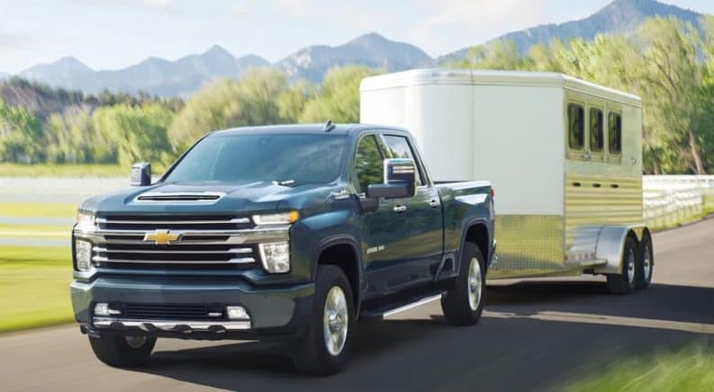 A black 2021 Chevy Silverado 2500 HD is towing a trailer down the road after winning the 2021 Chevy Silverado 2500 HD vs 2021 Ram 2500 comparison.