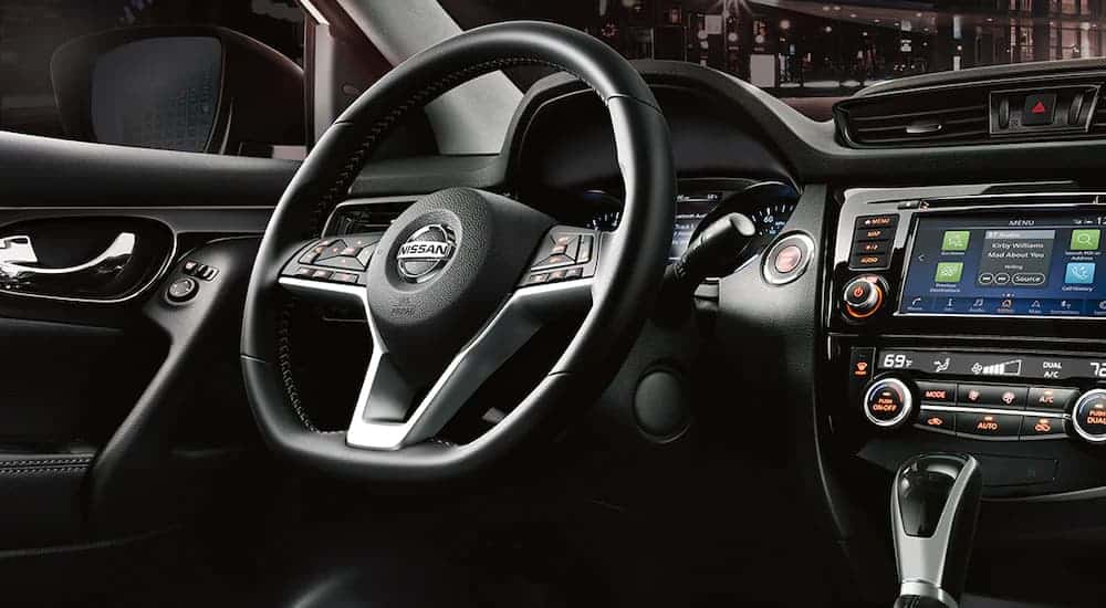 The black steering wheel and infotainment screen is shown in a 2021 Nissan Rogue Sport.