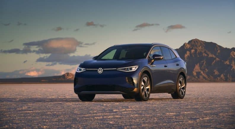 A dark blue 2021 Volkswagen ID.4 is parked in a desert in front of mountains.