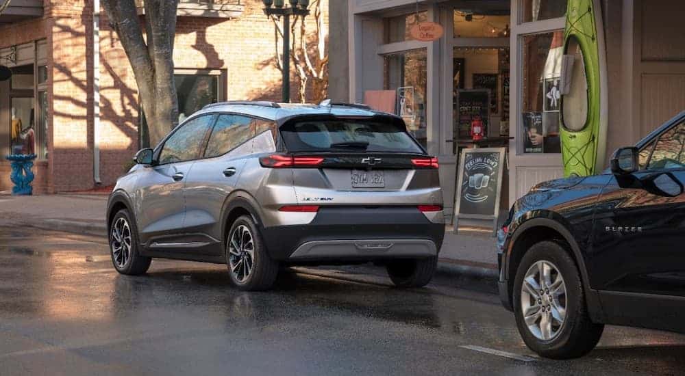 A silver 2022 Chevy Bolt EUV is parked on the street in front of a coffee shop.