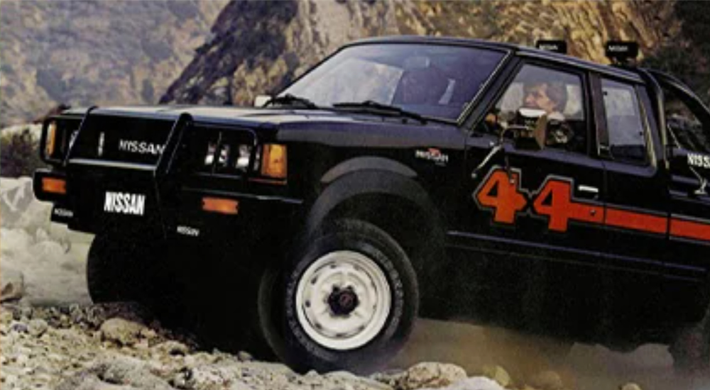 A black vintage Nissan Frontier is shown off roading in the mountains.