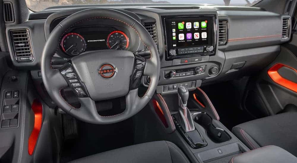 The black interior with red accents in a 2022 Nissan Frontier is shown.