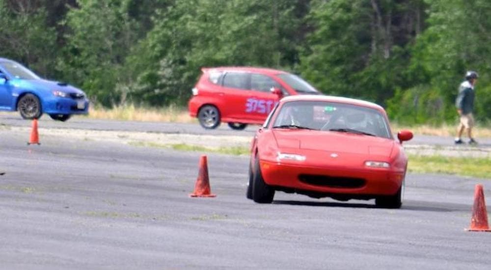 A popular car used in autocross racing, a 1991 Mazda Miata, is shown driving around a cone.