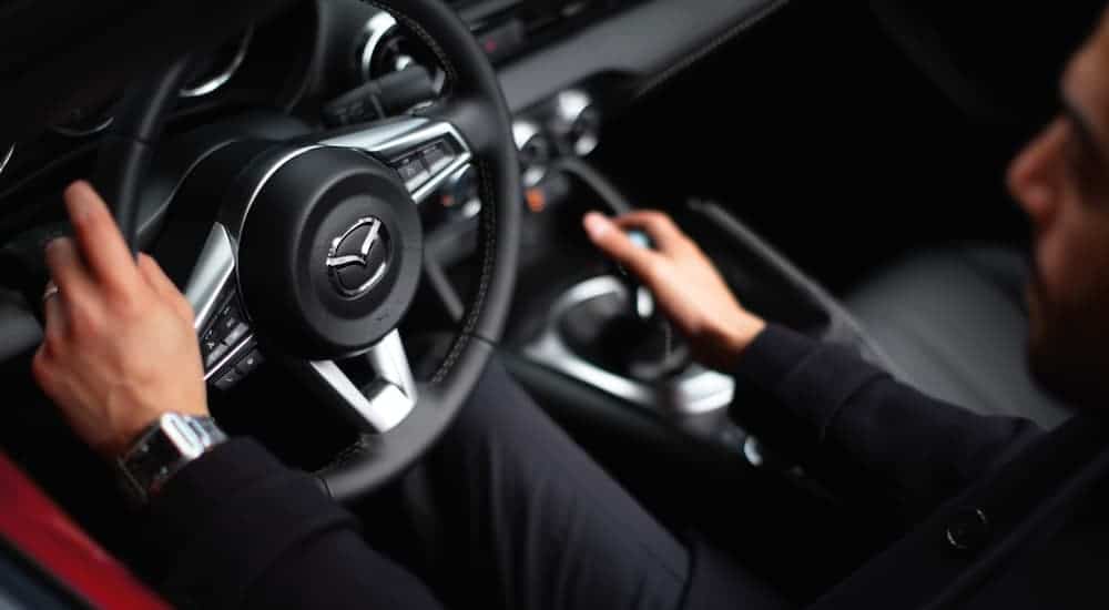 A close up shows the steering wheel and shifter in a 2021 Mazda MX-5 Miata.