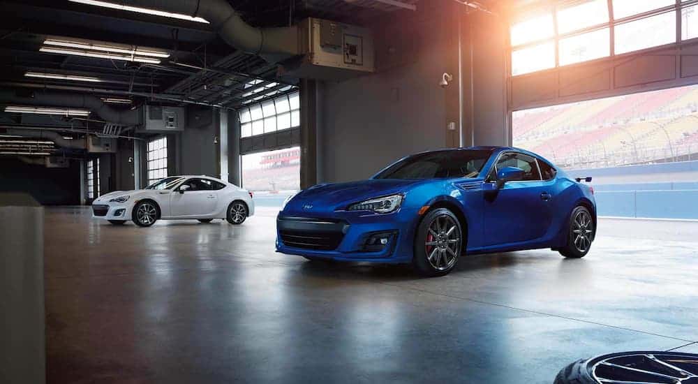 A blue and a white 2019 Subaru BRZ are shown parked in a garage after leaving a car dealer.