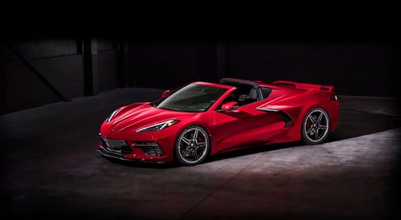 A red 2020 Chevy Corvette is shown from the side parked in a dark warehouse.
