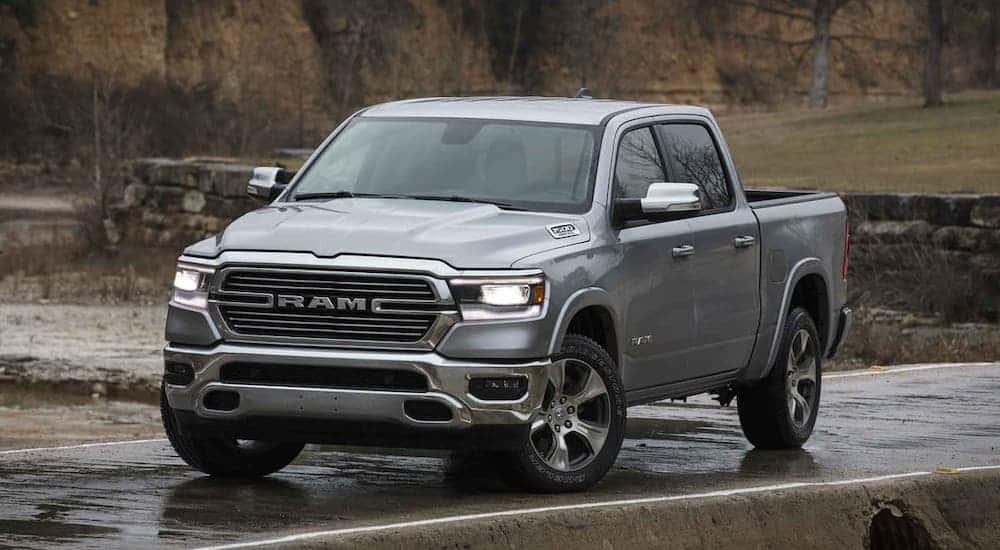 A gray 2021 Ram 1500 Laramie is driving on a winding road in the rain.