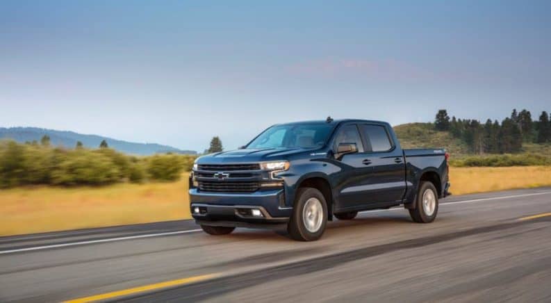 A blue 2021 Chevy Silverado 1500 RST is driving on an empty highway as part of the 2021 Chevy Silverado 1500 vs 2021 Ram 1500 comparison.