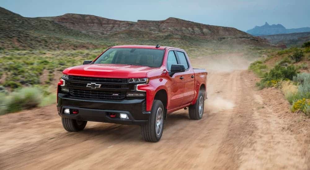 A red 2021 Chevy Silverado 1500 TrailBoss is driving on a dirt road.