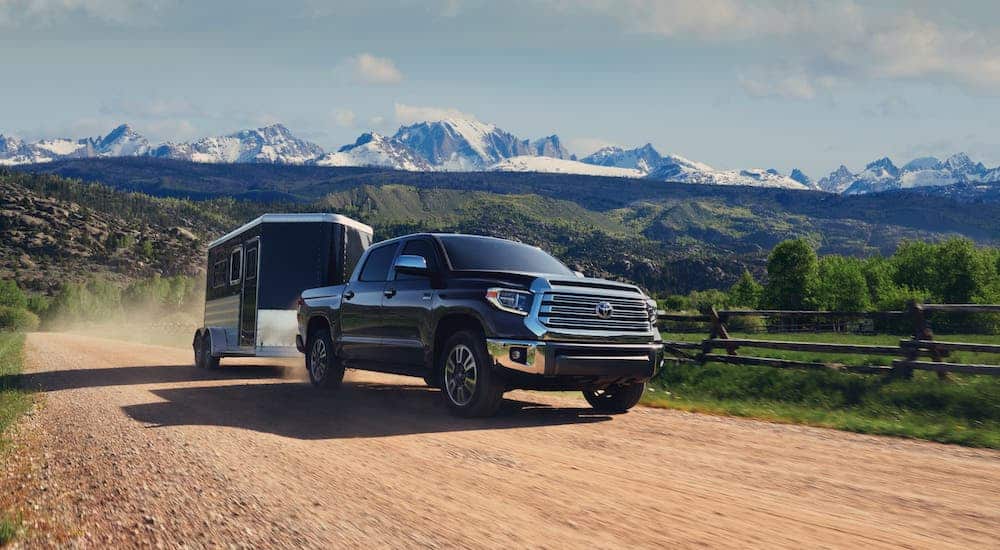 A black 2021 Toyota Tundra is towing an enclosed trailer in front of distant snow-covered mountains.