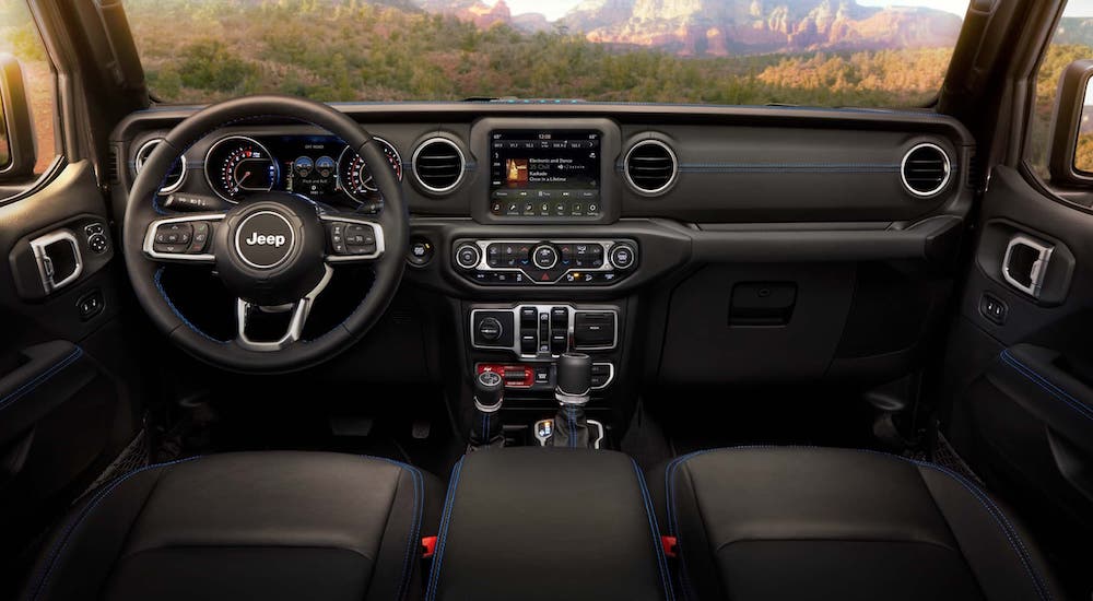 The black interior and dashboard with blue accent stitching is shown in a 2021 Jeep Wrangler 4xe.