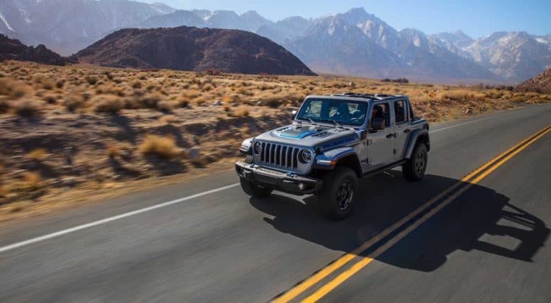 A silver 2021 Jeep Wrangler 4xe Unlimited is driving on a desert highway.
