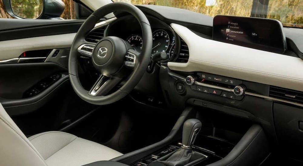 A closeup shows the infotainment screen and white dashboard in a 2021 Mazda3.