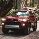 A red 2021 Toyota 4Runner drives through the woods.