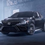 A black 2021 Toyota Camry is parked in a warehouse.