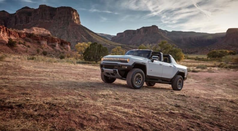 A white 2022 GMC Hummer EV Truck is parked on a trail in the desert.