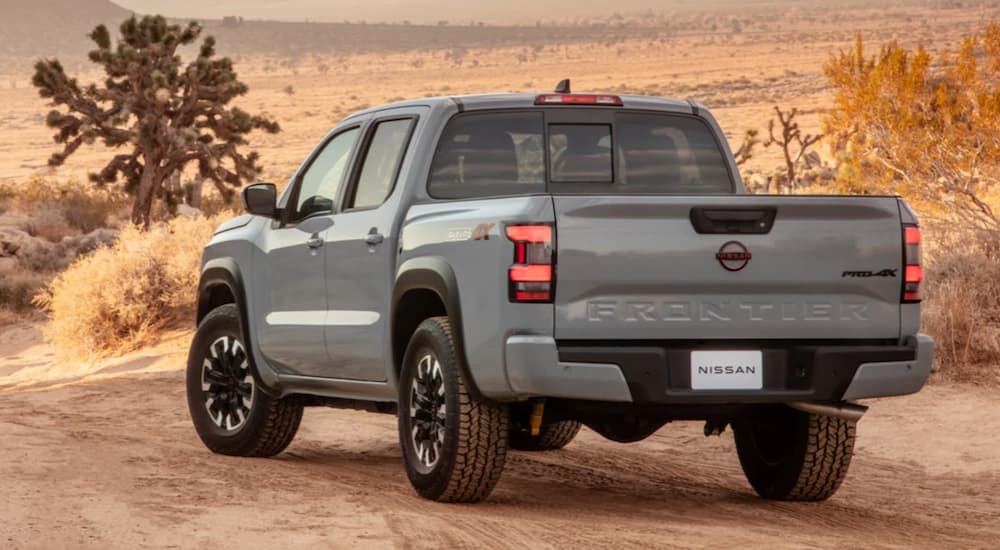 A grey 2022 Nissan Frontier is shown from the back driving in the desert.