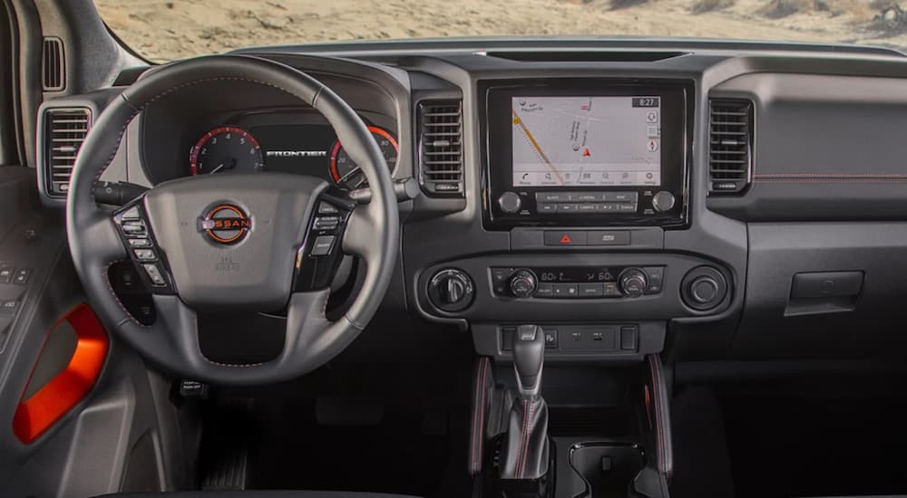 The interior of a 2022 Nissan Frontier shows a steering wheel and infotainment screen.