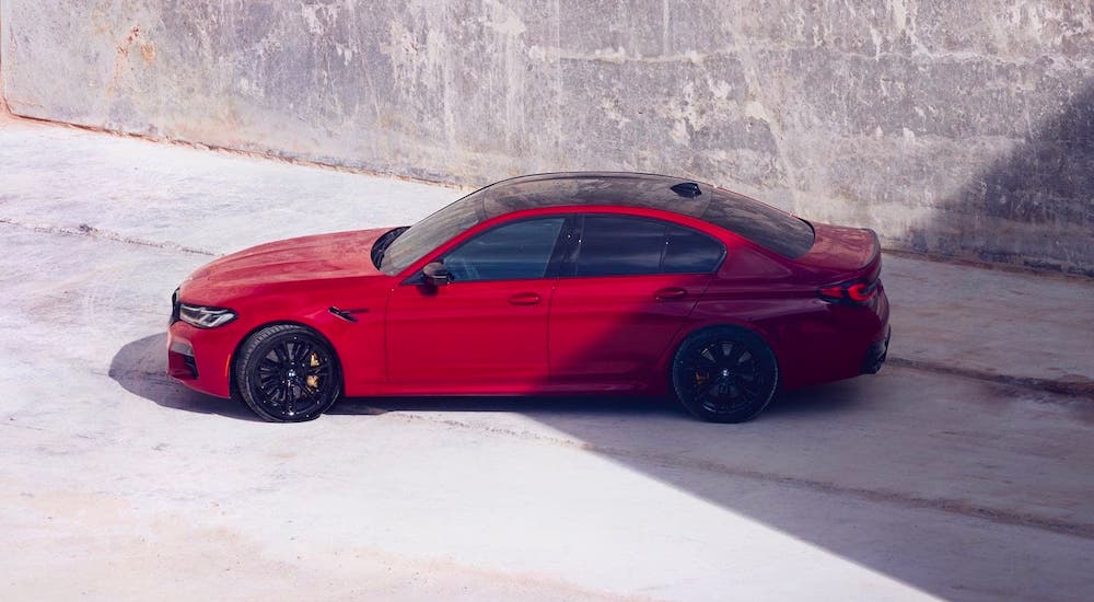 A red 2021 BMW M5 is shown from the side from a high angle in front of concrete.