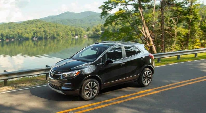 A black 2021 Buick Encore is shown driving past a lake after leaving a Buicks dealer near you.