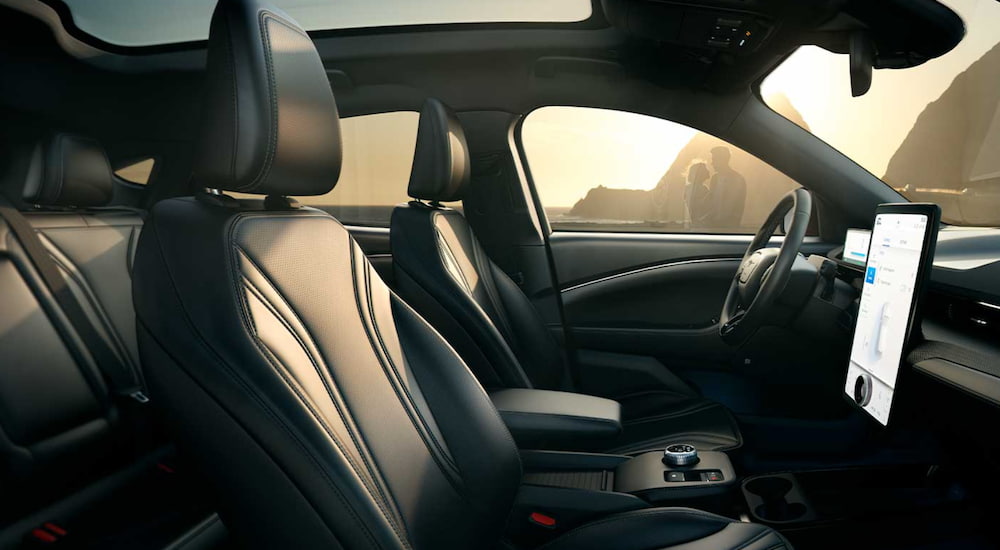 The interior of a 2021 Ford Mustang Mach-E shows the front seat, steering wheel and infotainment screen.