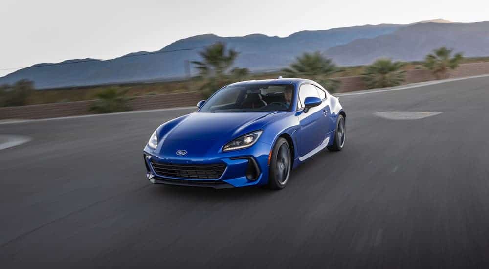 A blue 2022 Subaru BRZ from a Subaru Dealership is driving on an empty road.