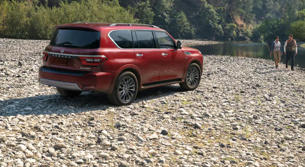 A red The 2021 Nissan Armada is shown parked next to a river.