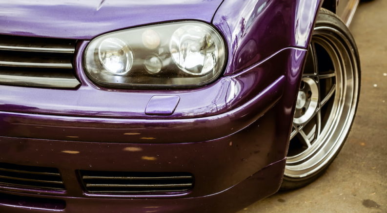 A purple car has a modified head light.