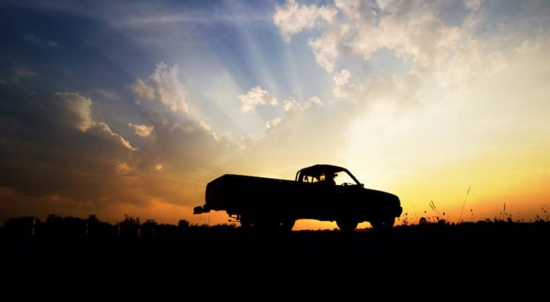 A popular used truck for sale near you is shown in silhouette while parked in a field at sunset.