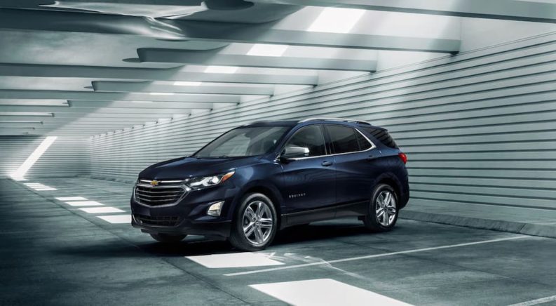 A dark blue 2021 Chevy Equinox is parked in a warehouse after winning 2021 Chevy Equinox vs 2021 Nissan Rogue comparison.