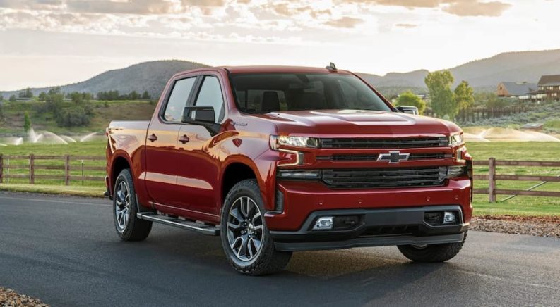 A red 2021 Chevy Silverado 1500 is parked on a road in front of a field after winning a 2021 Chevy Silverado 1500 vs 2021 Nissan Titan comparison.