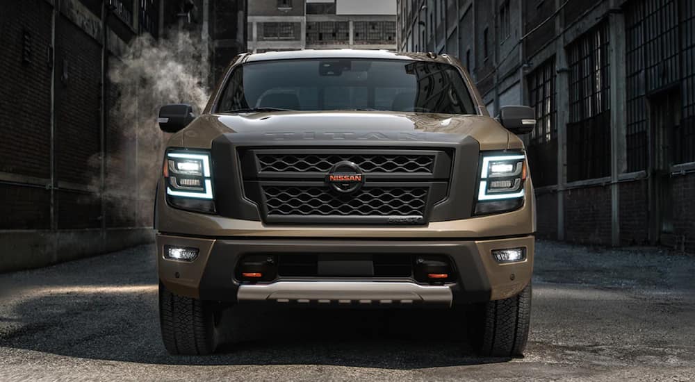 The front of a tan 2021 Nissan Titan is shown parked in an alleyway.