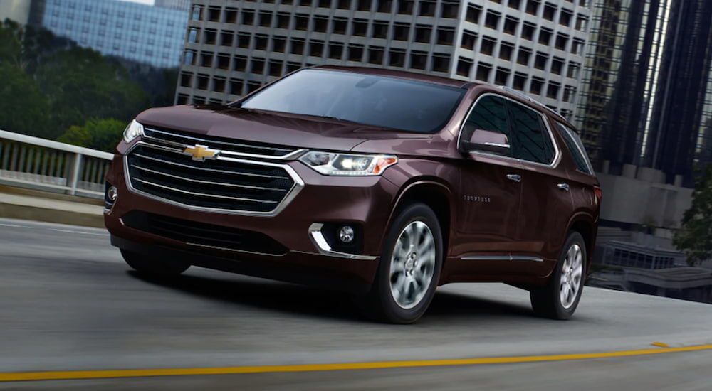 A maroon Chevy Traverse is shown from an angle driving through a city.