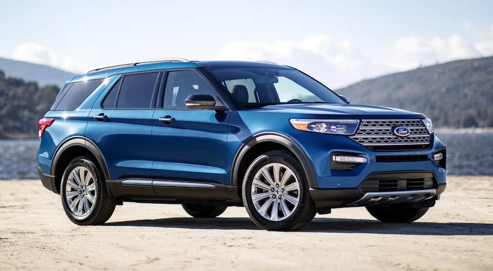 A blue 2021 Ford Explorer is parked in front of a lake.