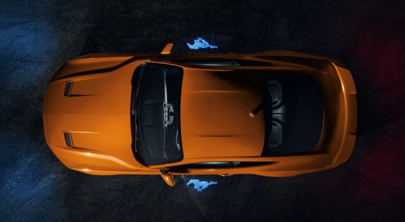 An orange 2021 Ford Mustang is shown from above at night.