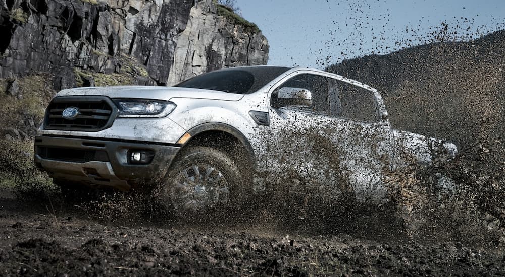 A white 2021 Ford Ranger is kicking up dirt as it off roads. 