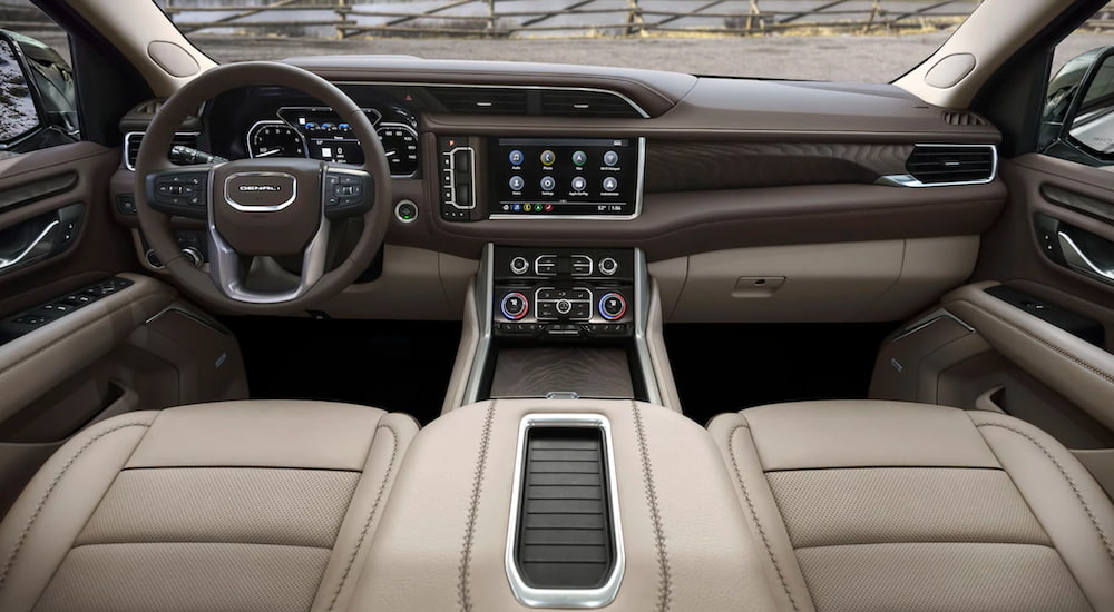 The interior of a 2021 GMC Yukon Denali shows the front seats, steering wheel and infotainment screen.
