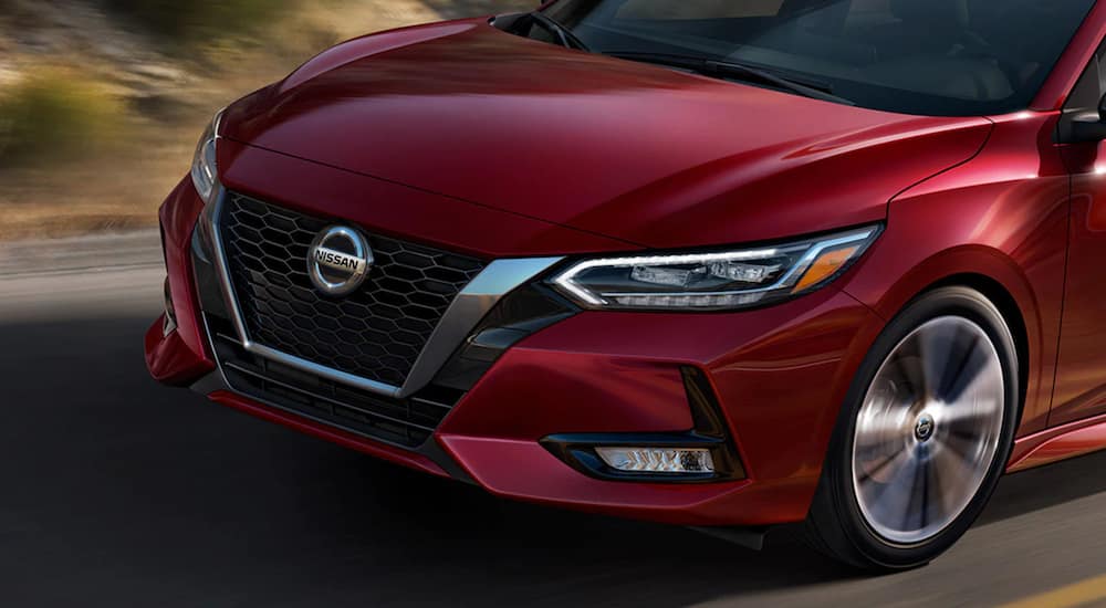 A red 2021 Nissan Sentra shows a close up of the front of the car driving on an open road.