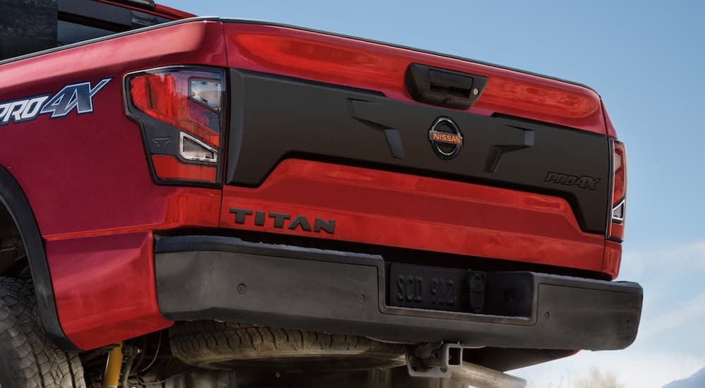 The rear of a red 2021 Nissan Titan Pro4X is shown in front of a blue sky.