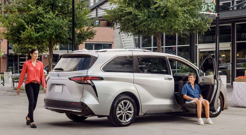 A handicapped man is being lowered out of the passenger seat in a silver 2021 Toyota Sienna.