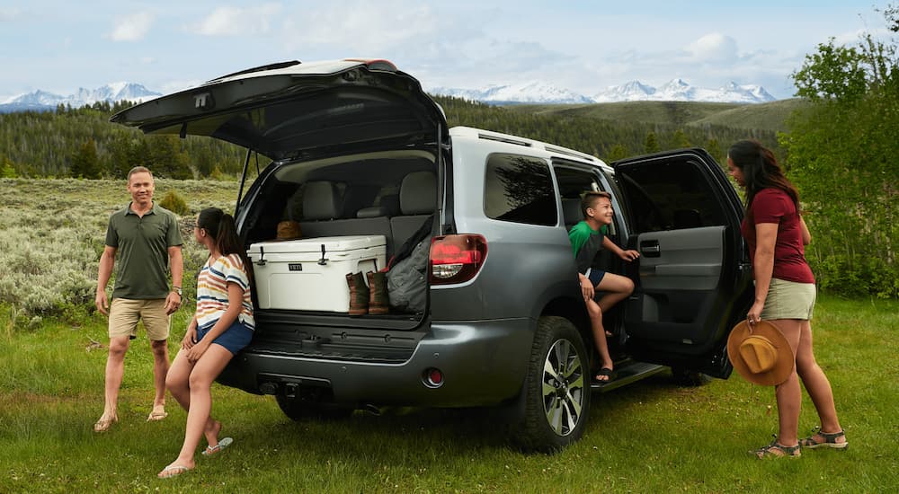 The trunk of a grey 2021 Toyota Sequoia is open with a cooler inside and a family moving around the vehicle.