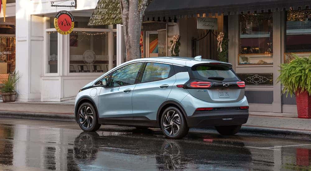 A light blue 2022 Chevy Bolt EV is shown from the side on a city street.