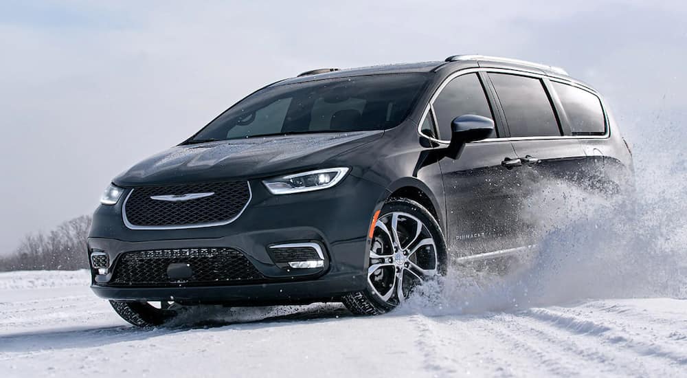 A black 2021 Chrysler Pacifica is driving through a snowy field.