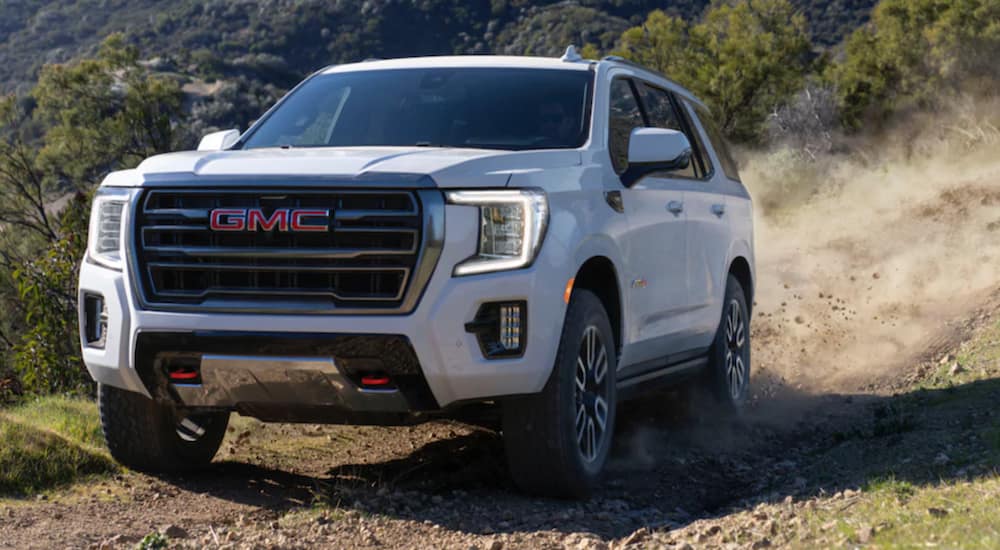 A white 2021 GMC Yukon AT4 is shown from the font while off-roading.