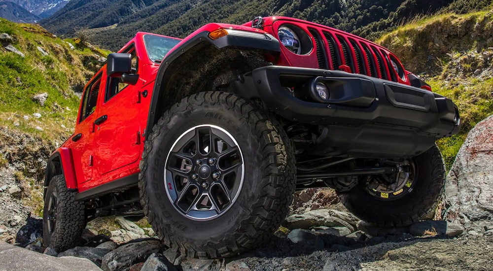 A red 2021 Jeep Wrangler is parked on a pile of rocks.