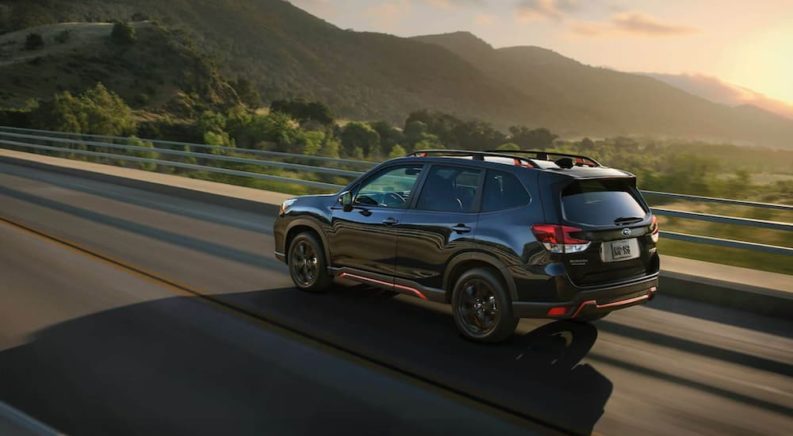 A black 2021 Subaru Forester is shown from a side angle driving on an open road after leaving a Subaru Forester Dealer.