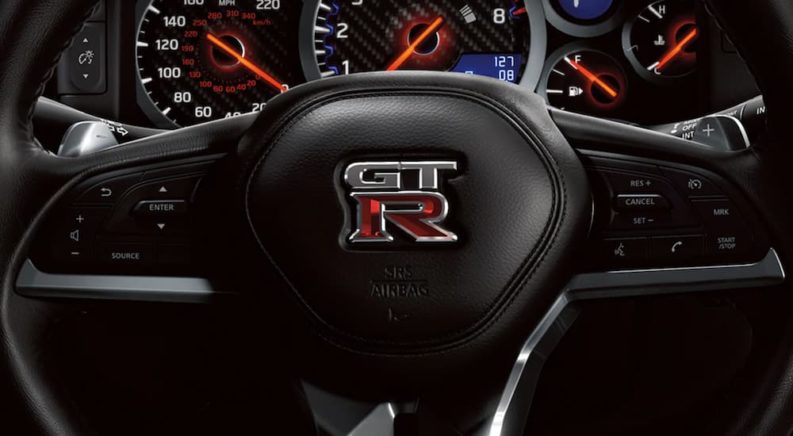 The steering wheel of a 2021 Nissan GT-R shows the GT-R emblem.