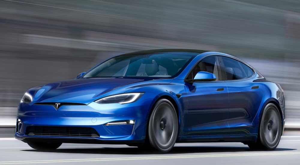 A blue used 2019 Tesla Model S is driving down a road.