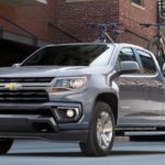 A grey 2021 Chevy Colorado is driving on a city street after winning a 2021 Chevy Colorado vs 2021 Toyota Tacoma comparison.
